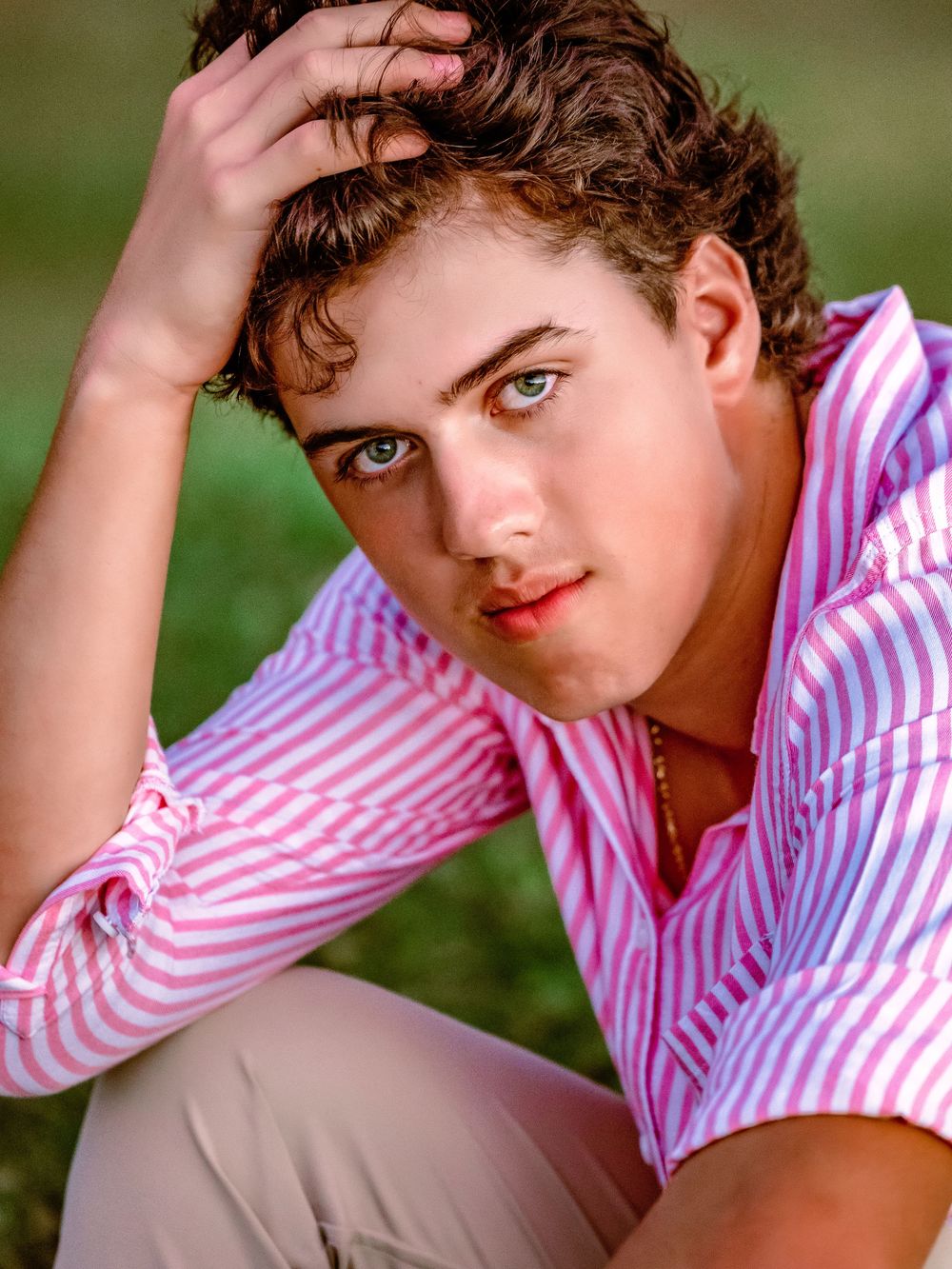 A person in a pink and white striped shirt poses outdoors in a series of artistic portrait shots.