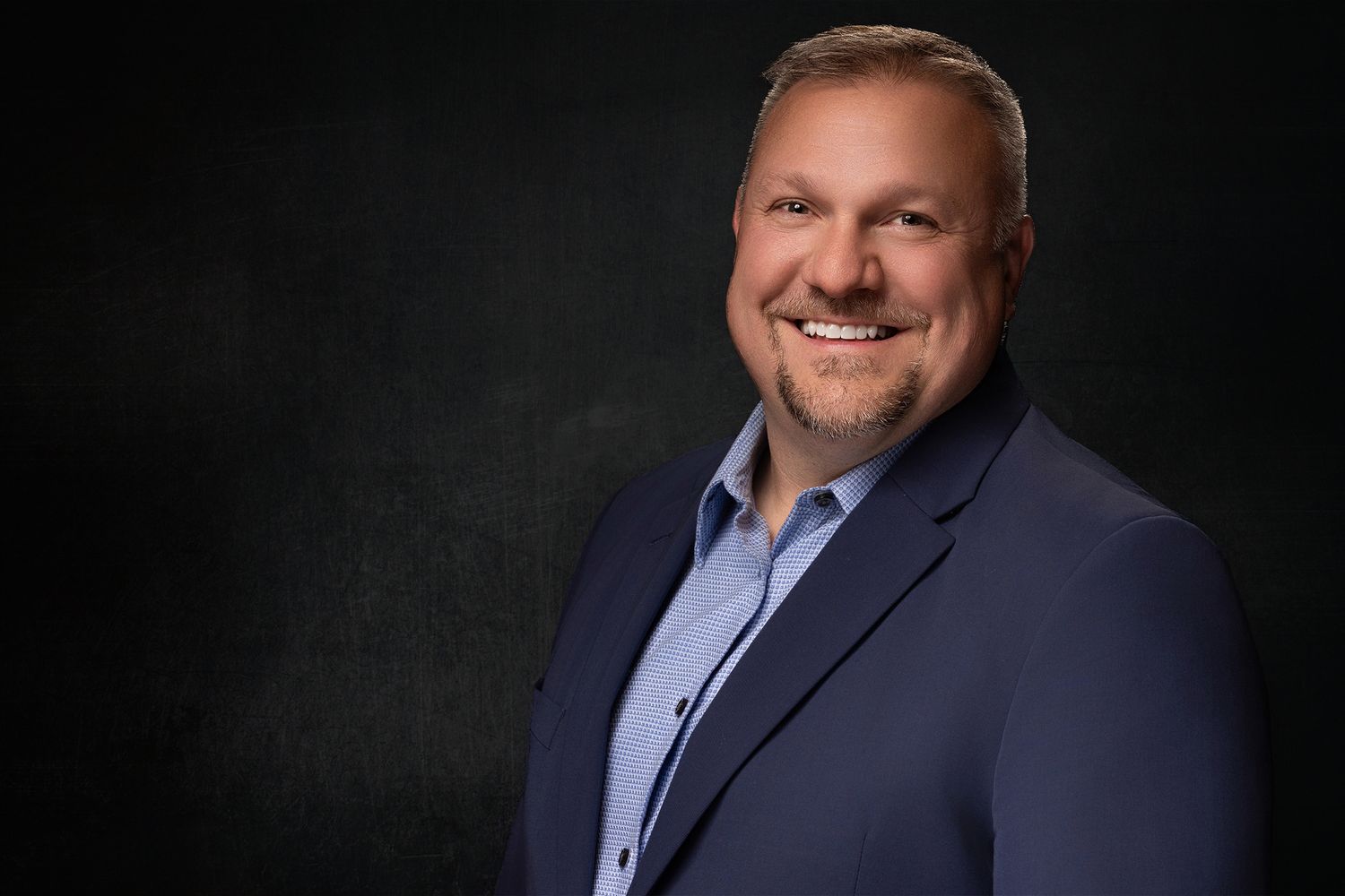 Realtor headshot - Lehigh Valley. Professional headshot portrait with navy blazer and light blue dress shirt against dark background.