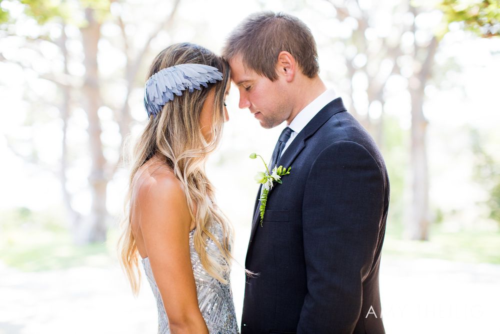 Bride wearing floral headpiece and groom in navy suit sharing an intimate forehead-to-forehead moment.