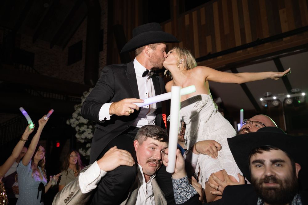 A celebratory moment as newlyweds are lifted on chairs during traditional wedding dance celebrations.
