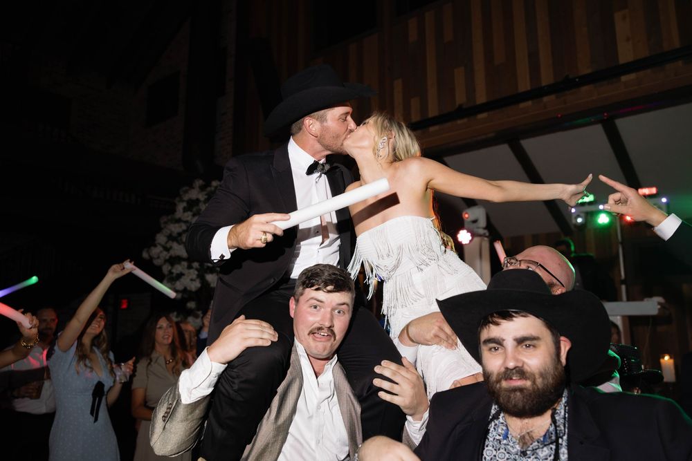 Wedding reception guests dancing and celebrating on a crowded dance floor at night.