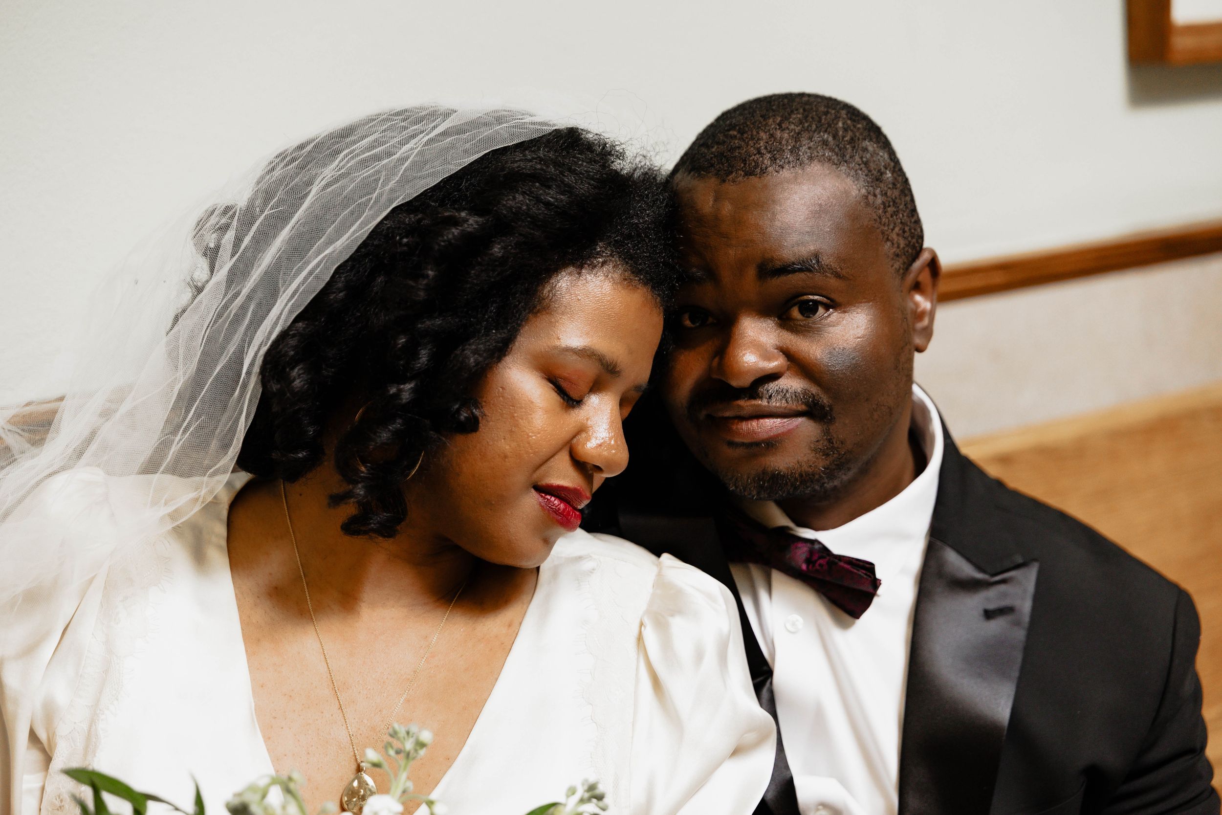 Intimate wedding portrait of newlyweds sharing a tender moment in formal attire.