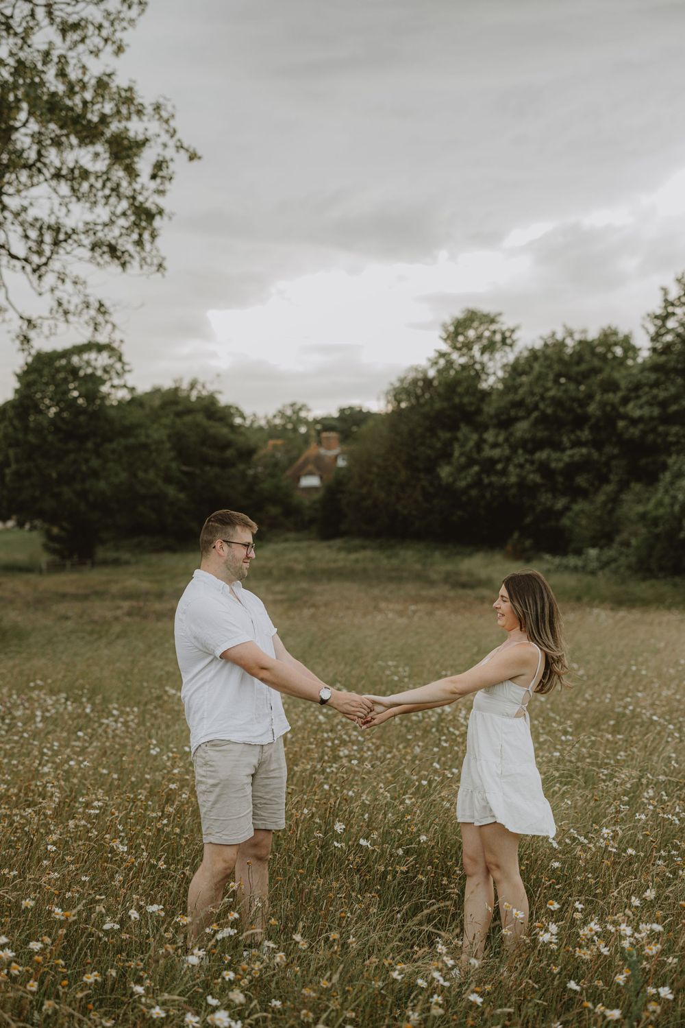 A playful couple dances and spins through a meadow filled with delicate white flowers.