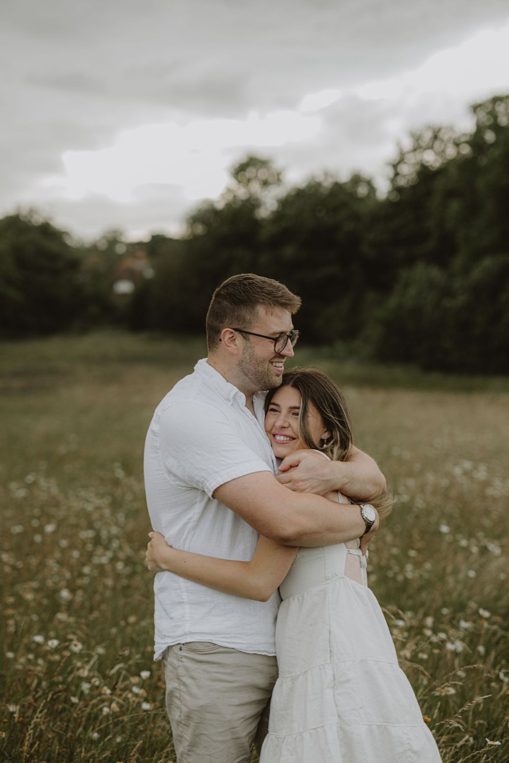 A tender moment captured as a couple hugs intimately in a flowering summer field.