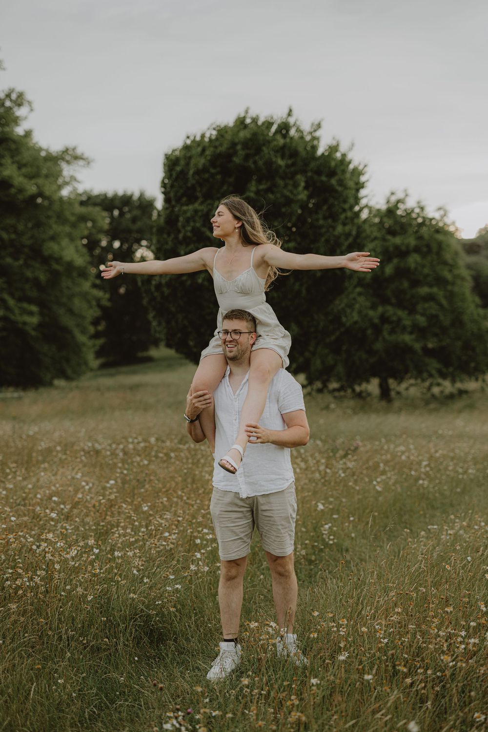 A playful couple dances and spins together in a wildflower meadow on a summer day.