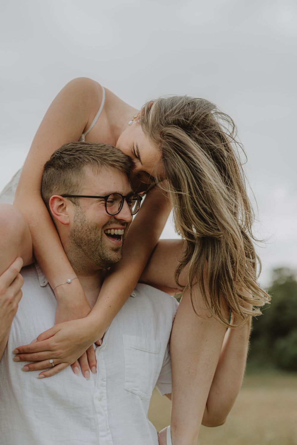 A romantic couple shares intimate moments while playing in a sunlit field.