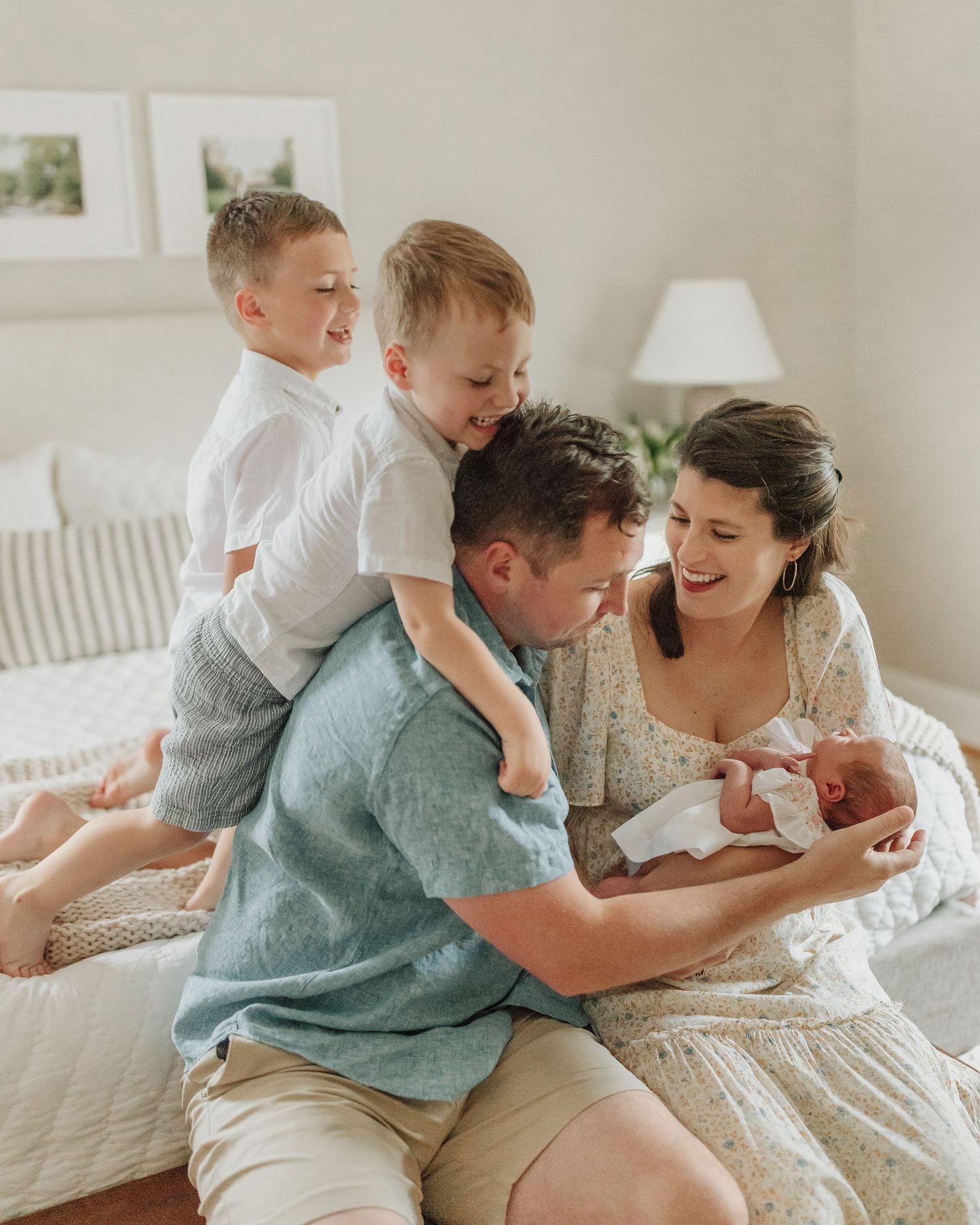 A family shares intimate moments and laughter while bonding with their newborn on a bed.