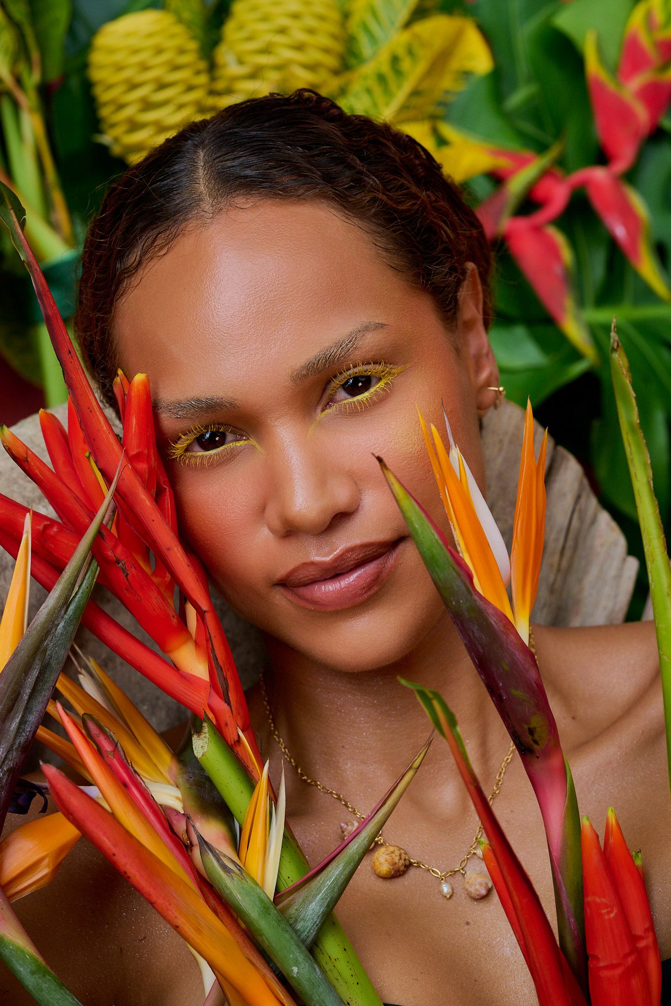 Vibrant heliconia flowers in red and yellow hues create a tropical backdrop for a portrait against lush green foliage.
