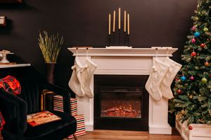 A festive living room with a decorated Christmas tree, glowing candles, and a white fireplace mantel with stockings.