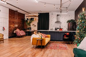Modern studio apartment interior with track lighting, hardwood floors, and minimalist decor across multiple connected spaces.
