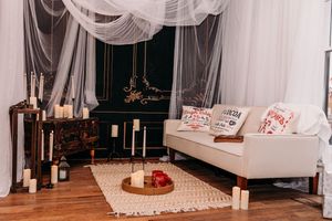 Elegant white sheer curtains drape across a room with wooden floors and decorative holiday accents.