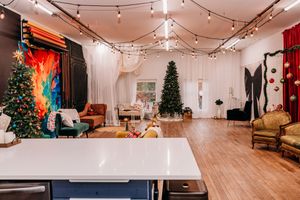 String lights illuminate a modern dance studio space with hardwood floors and Christmas trees in the corners.