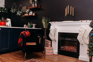 Modern living room with dark walls features a fireplace, white trim, and holiday decorations.