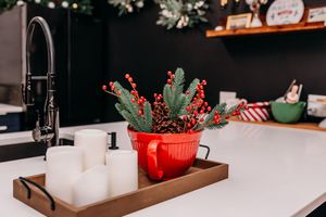 String lights and festive holiday decorations adorn a rustic wooden table setting with greenery and red accents.