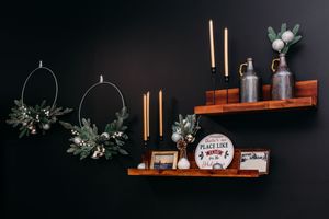A cozy dark room interior with floating wooden shelves displaying decorative items against a black wall.