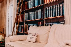A cozy reading nook with plush cushions and built-in bookshelves filled with vintage hardcover books.