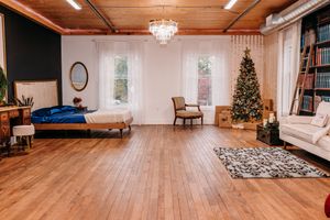 A panoramic view of an elegant living room interior with hardwood floors, chandelier, and Christmas tree decorations.