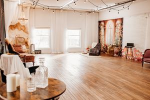 Bright studio space with wooden floors, white walls, string lights, vintage decor and window panels. Photography Studio in Wayland, MI