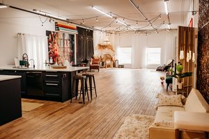 Panoramic view of a rustic studio space with wooden floors, exposed beams, and natural light streaming through windows. Photography Studio