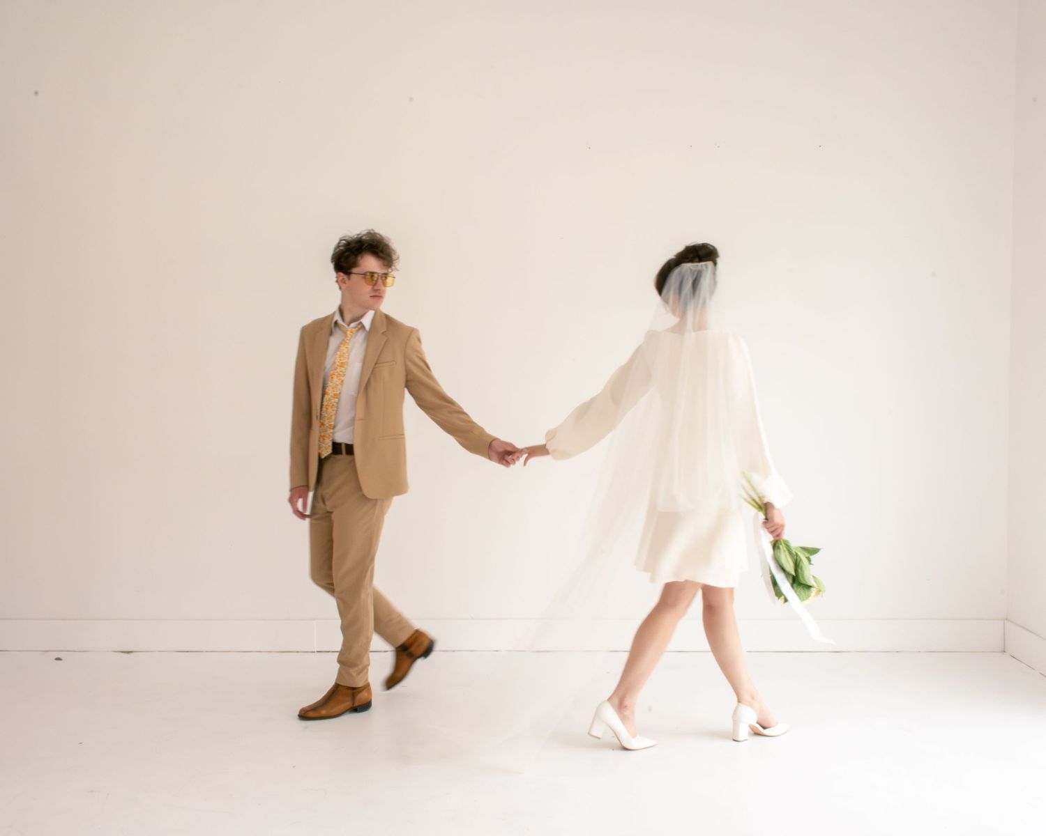 Bride and groom hold hands in a cinematic moment in studio bridals in Utah.