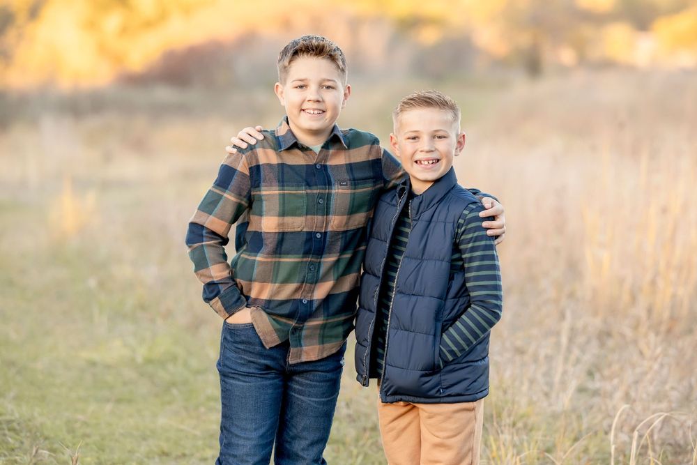 Two children in coordinated outfits stand together during a fall photo session. Clear Lake Photographer. Mason City Photographer.