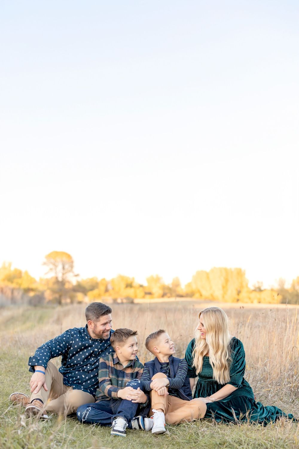 Family relaxing together on grass during sunset photoshoot. Clear Lake Photographer. Mason City Photographer.