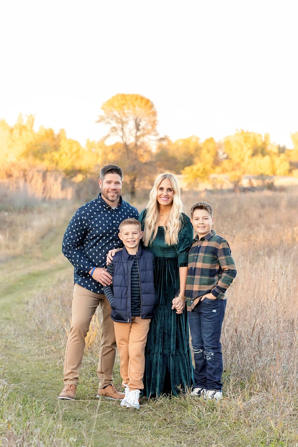 Family portrait session in a golden field during sunset with warm autumn lighting.