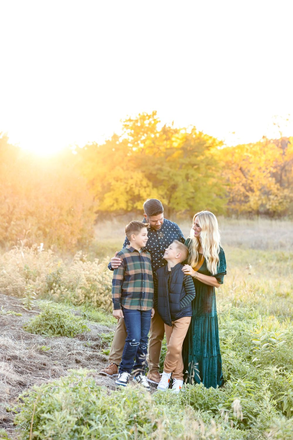 Family portrait session in a field with tall grass and warm sunlight.