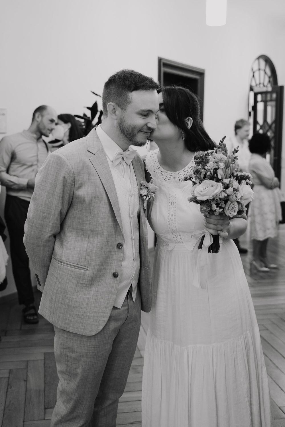 Black and white photo of a bride and groom sharing a tender moment, bride holding a bouquet at their wedding reception. Berlin