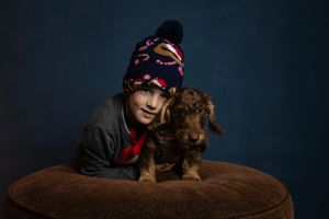 Fiú karácsonyi sapkában barna szálkás szőrű tacskóval