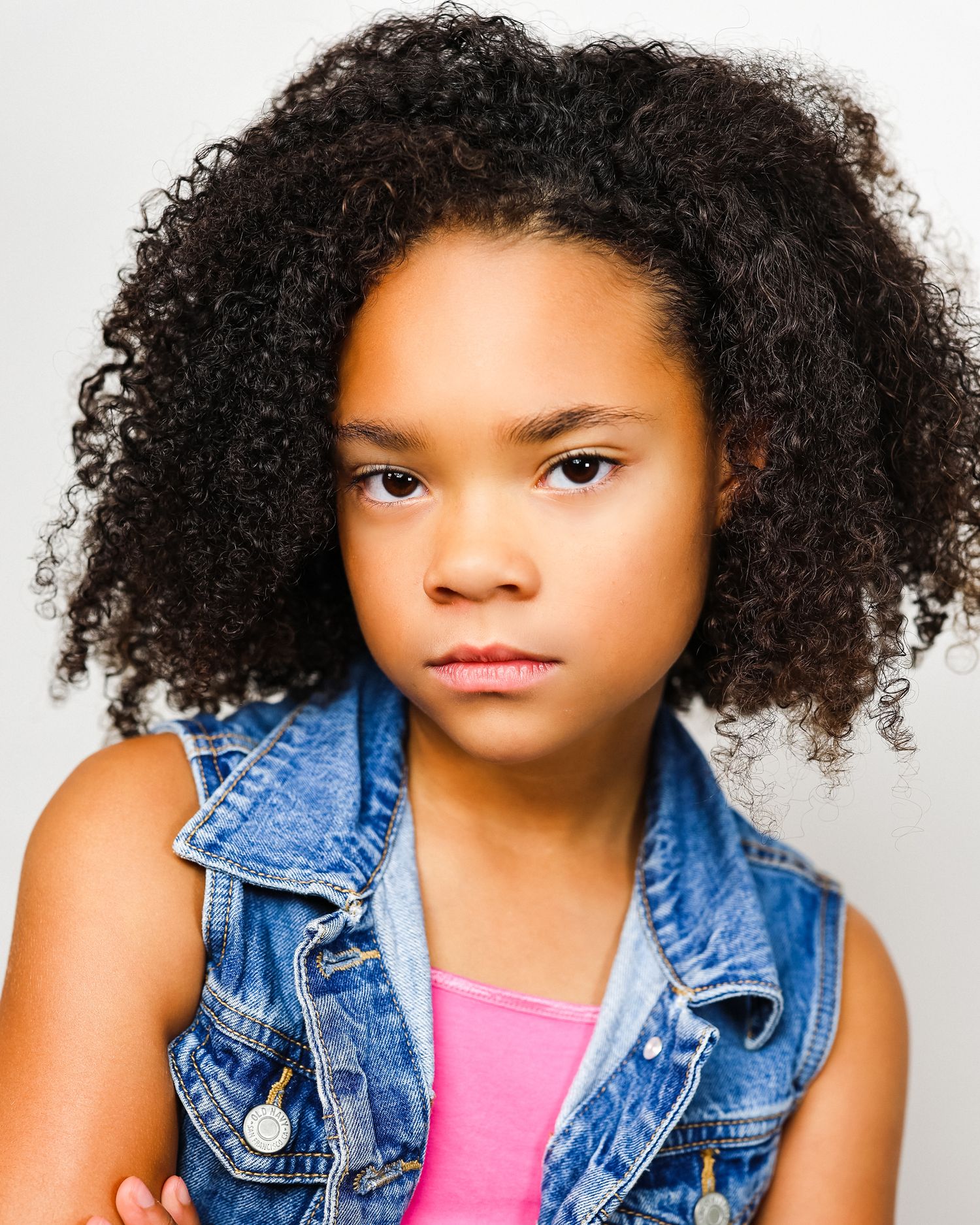 Serious dramatic portrait with natural curly hair and denim vest.