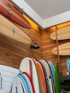 Collection of colorful surfboards displayed on wooden wall with warm lighting.