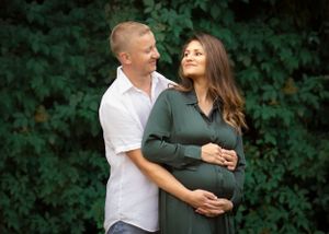 Couple shares intimate moment outdoors during maternity photoshoot.