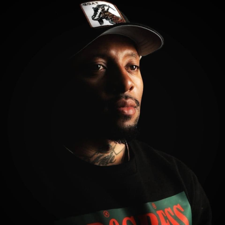 Person wearing a cap is shown in dramatic low-key lighting against a dark background.