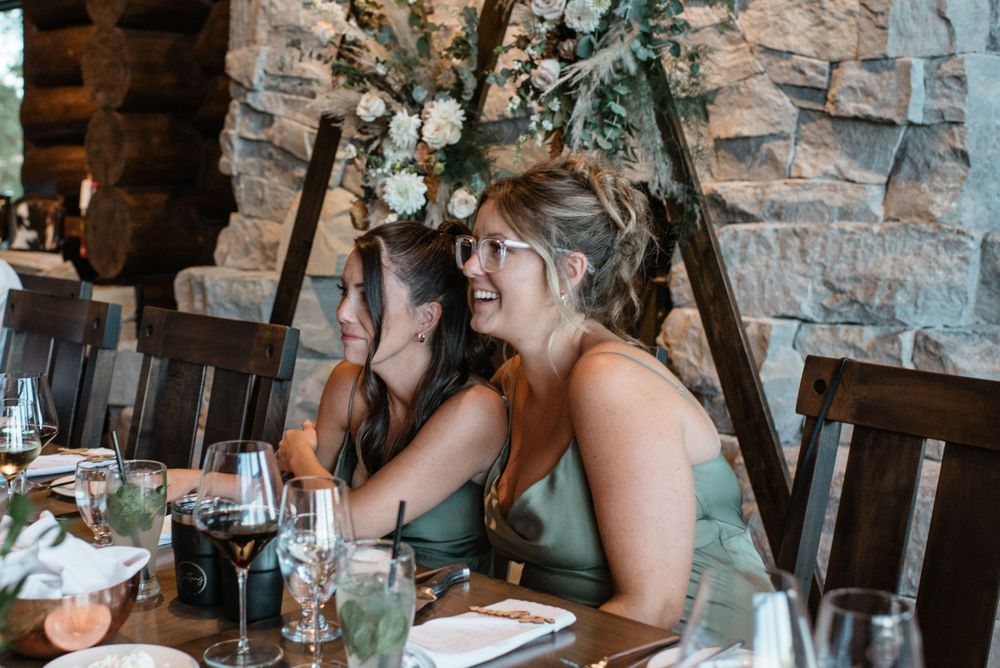 Joyful guests laugh together during a rustic restaurant dinner celebration with stone walls and wine glasses.