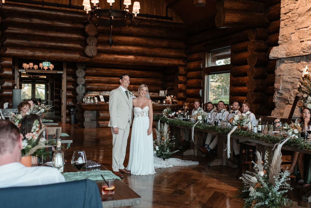 Elegant rustic log cabin wedding reception with floral tablescapes and chandeliers creating a romantic atmosphere.