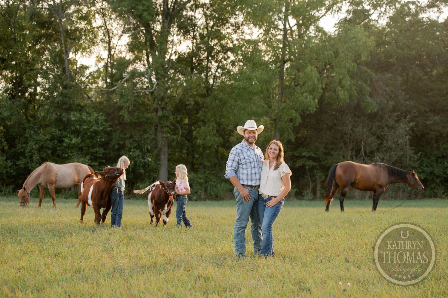 A group with horses gather in a serene meadow during sunset.