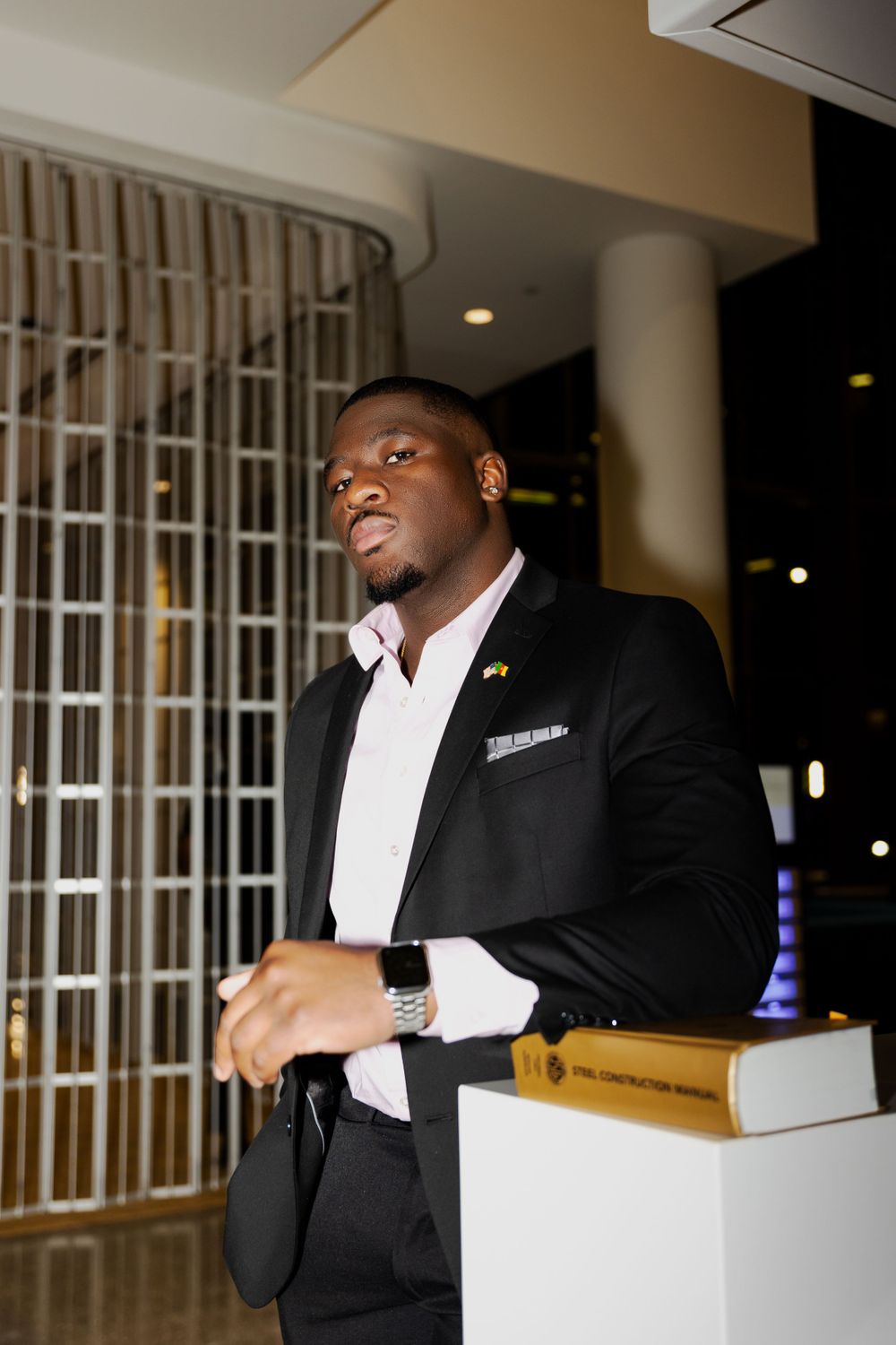 Professional in black suit standing in modern building interior.