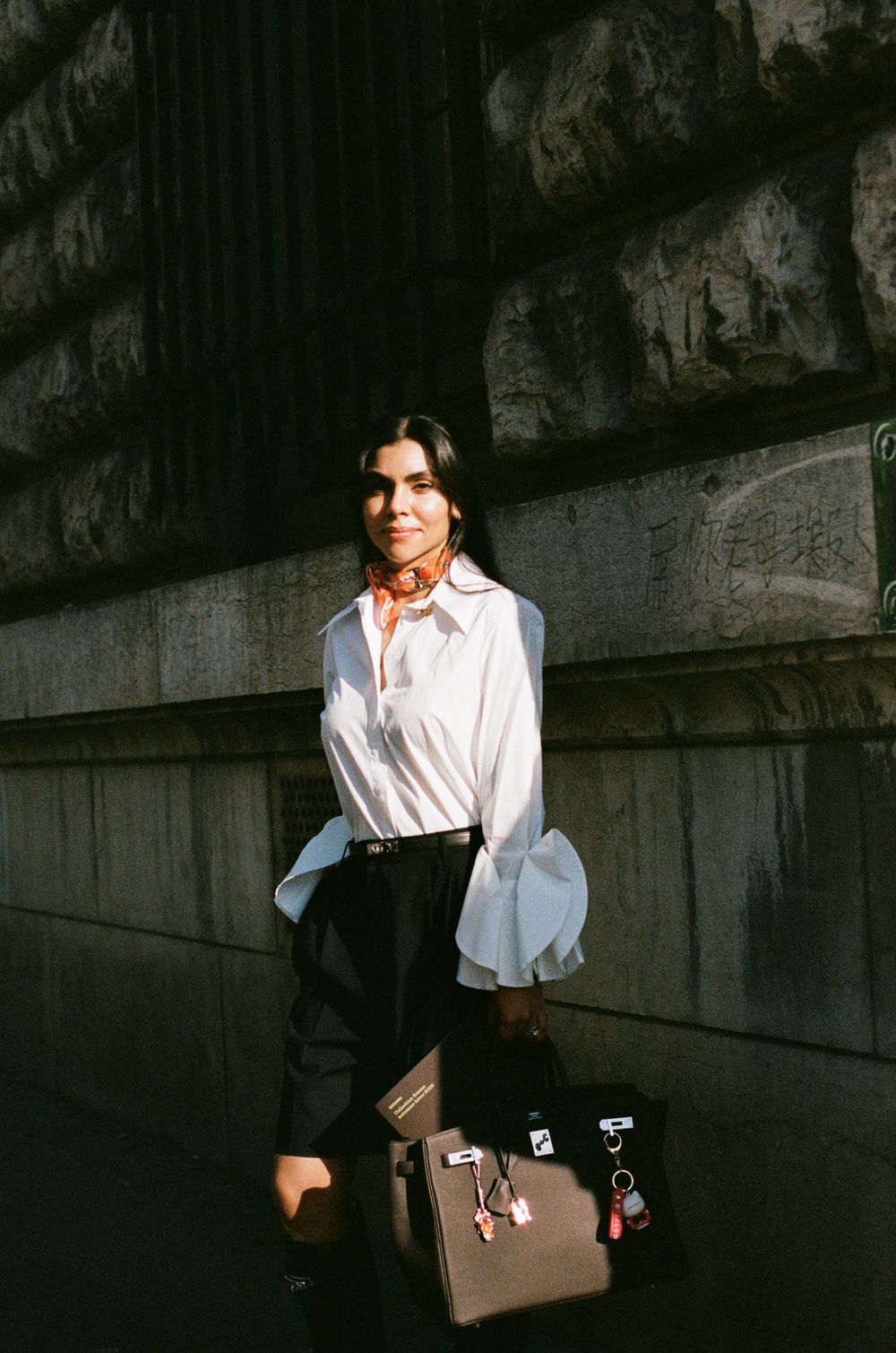 Vintage style fashion photo showing a white blouse with bell sleeves paired with dark shorts and brown leather bag.