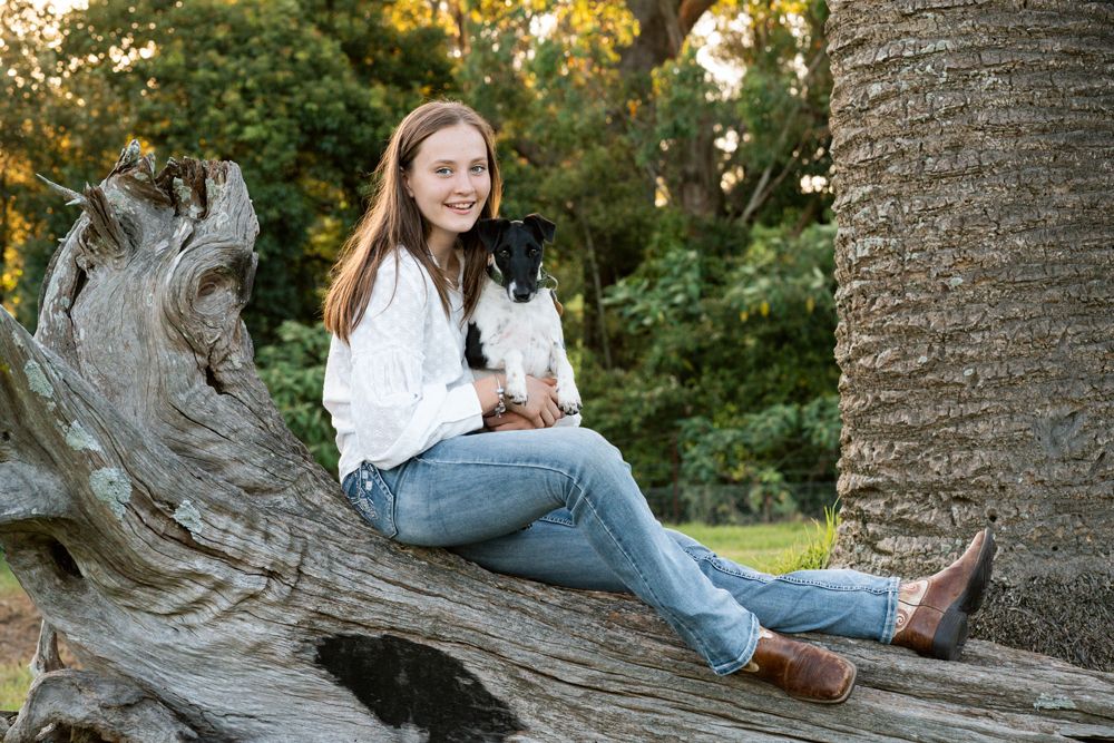A girl and her Fox Terrier sharing a sweet moment during a dog-friendly family photoshoot in Central Coast, NSW, captured at golden hour
