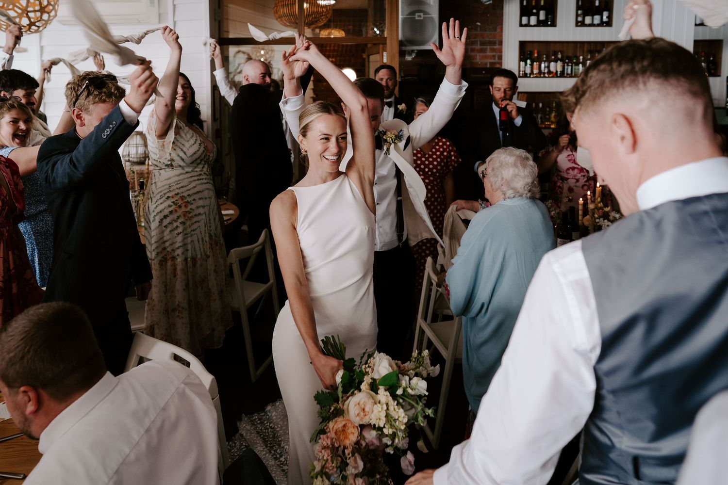 Wedding guests cheering Bride and grooms entrance to wedding breakfast at tunnels beach wedding venue in north devon
