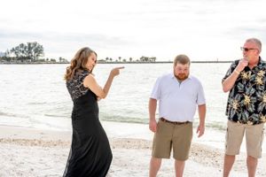Three people engaged in animated conversation on a sunny beach.
