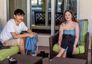 Two people relaxing on outdoor patio furniture at a resort setting.