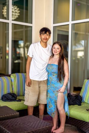 Couple posing together on outdoor patio with striped cushioned seating.