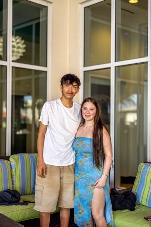 Couple standing together on outdoor patio with windows and green cushioned seating.