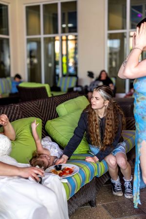 Friends relaxing on outdoor patio furniture with colorful striped cushions and green accent pillows.