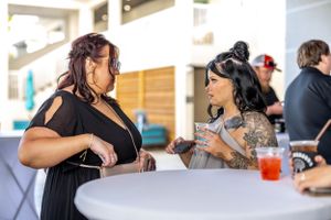 Two guests engaged in animated conversation at a white table during an outdoor event.
