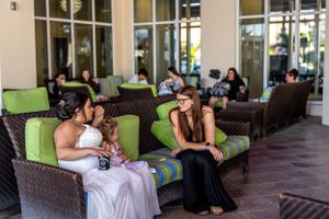Guests relaxing on wicker patio furniture with bright green cushions during an outdoor event.