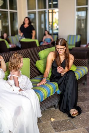 Guests chatting while relaxing on outdoor patio furniture with green and striped cushions.