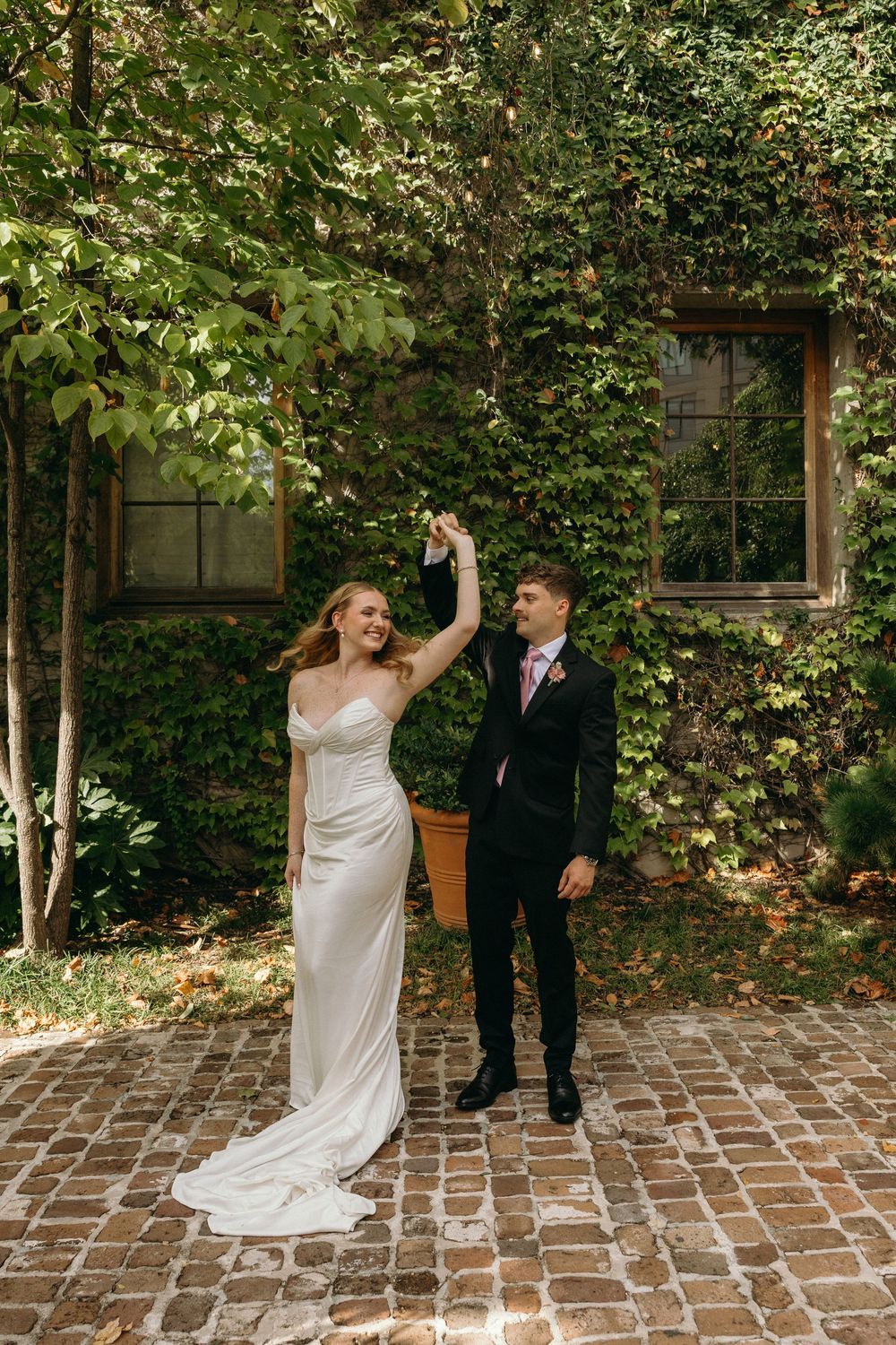 A couple shares a joyful moment on a brick patio surrounded by lush greenery during their wedding celebration in Atlanta